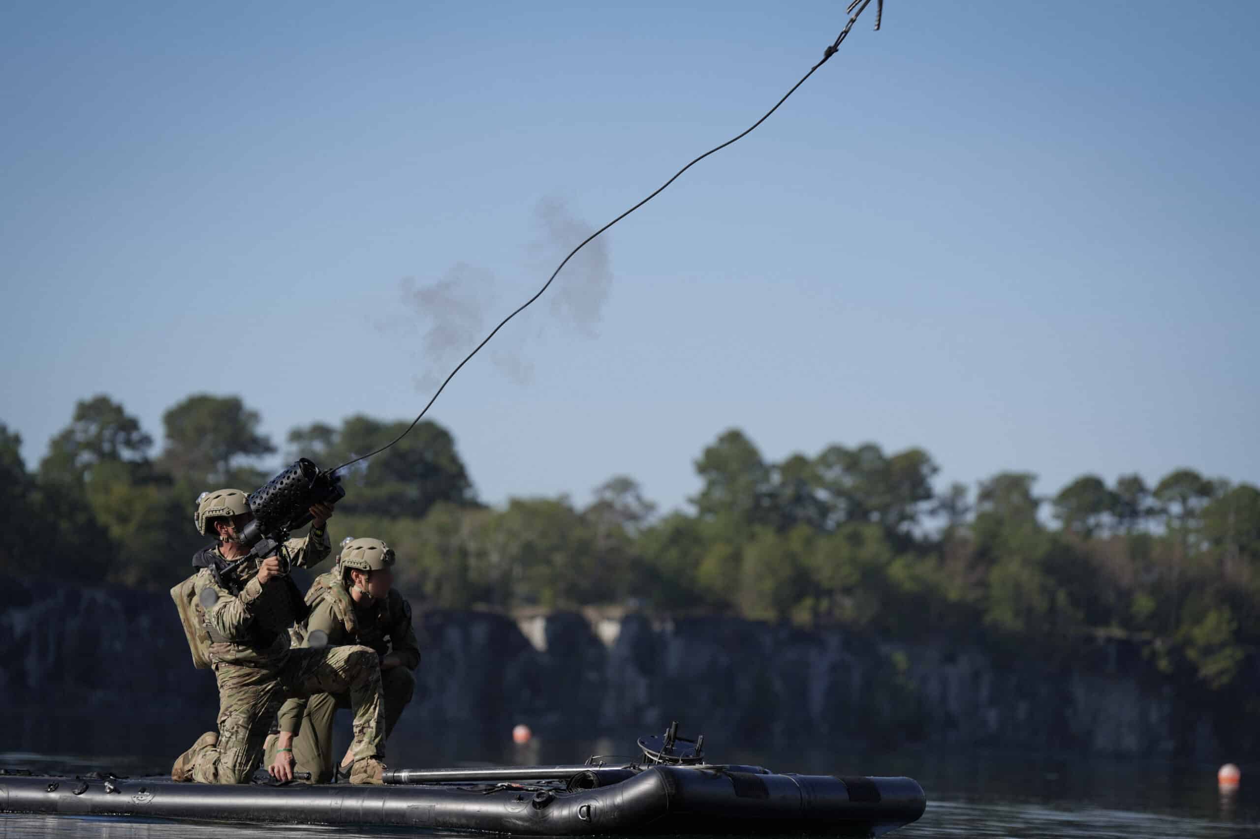 Soldiers in tactical gear firing a mounted weapon from an inflatable boat on water